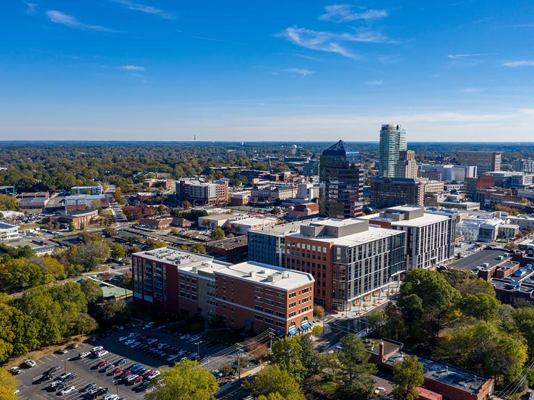 Durham NC cityscape blending historic brick architecture with modern buildings, symbolizing comprehensive air duct and mold remediation for diverse properties.